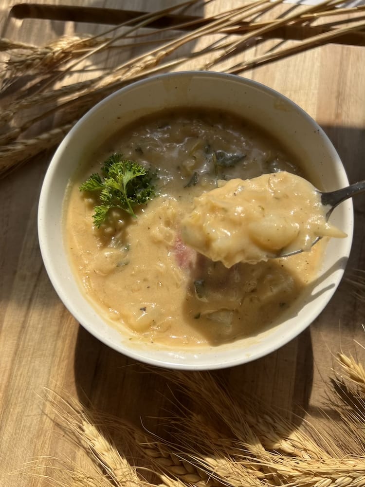 Creamy Kielbasa Sauerkraut Soup with spoon showing potatoes