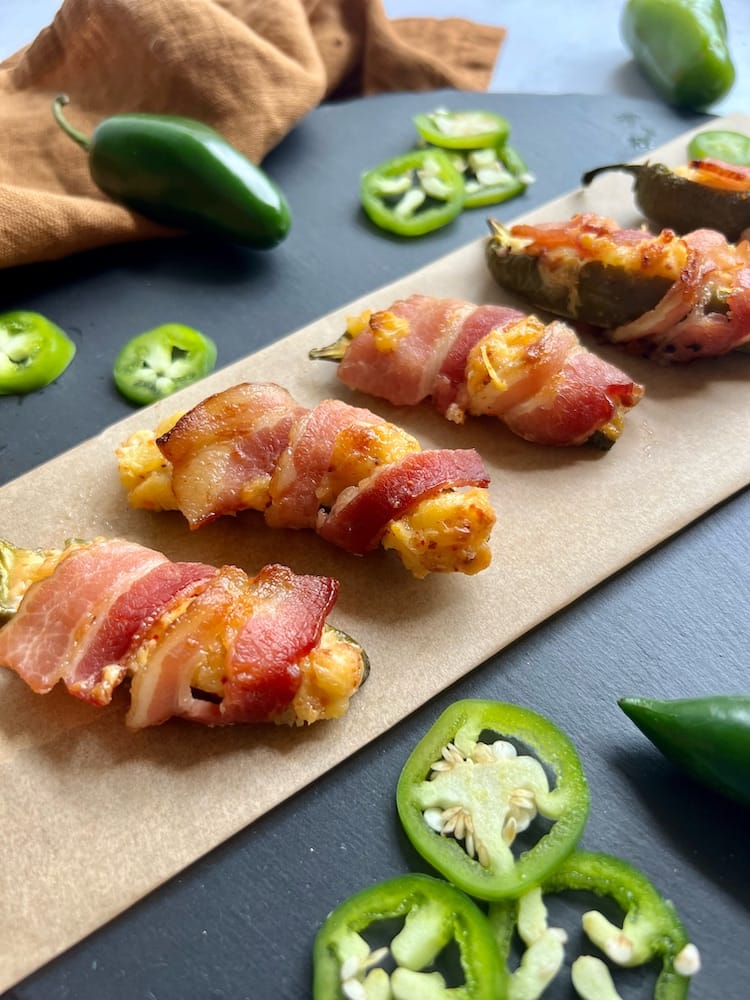 Bacon-wrapped pineapple jalapeno poppers laid on parchment paper