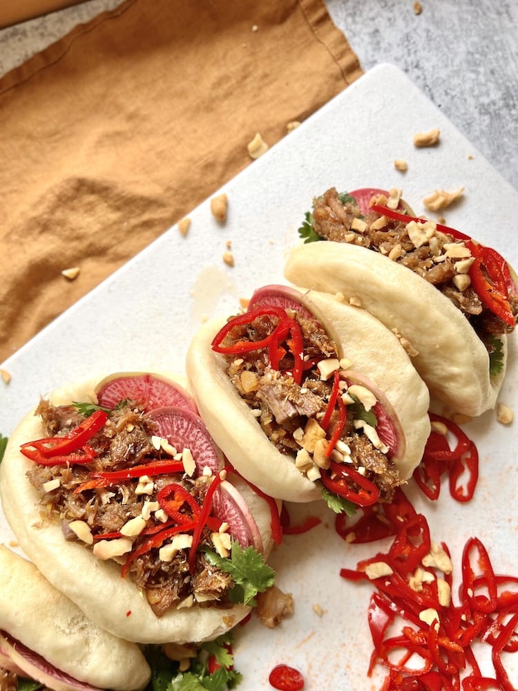Pork Belly Bao topped with cilantro, sliced chiles, and chopped cashews