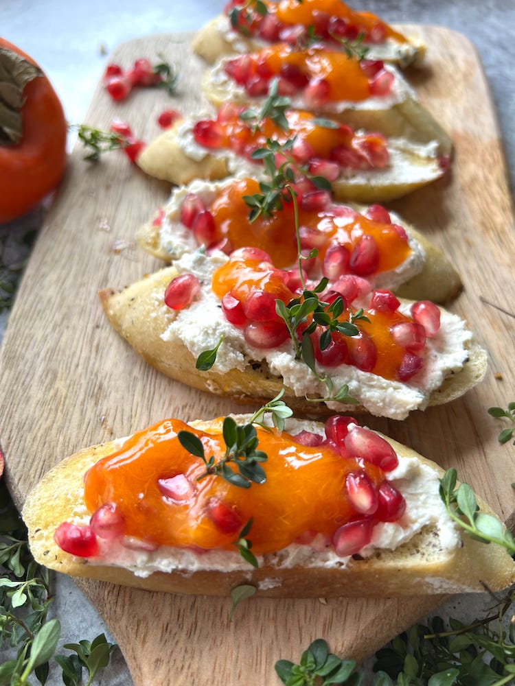 Pomegranate Persimmon Crostini arranged on a wooden cutting board