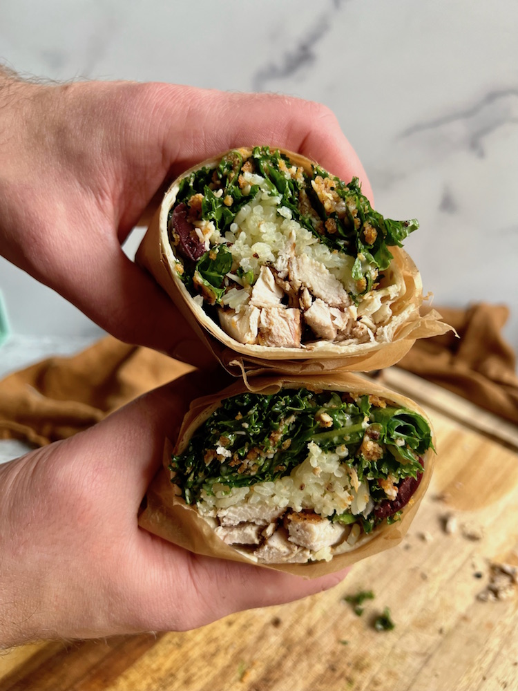 Grilled Chicken Caesar Wrap cut in half and held in hands showing the cut ends toward the camera