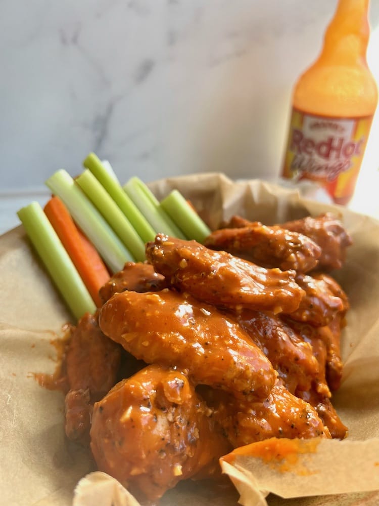 Garlic Hot Wings in a serving basket with cut celery and carrot sticks