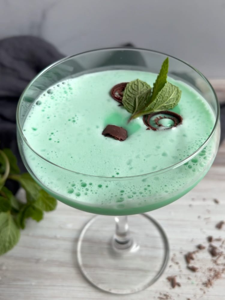 Grasshopper Cocktail in a coupe glass with mint and chocolate curls as garnish