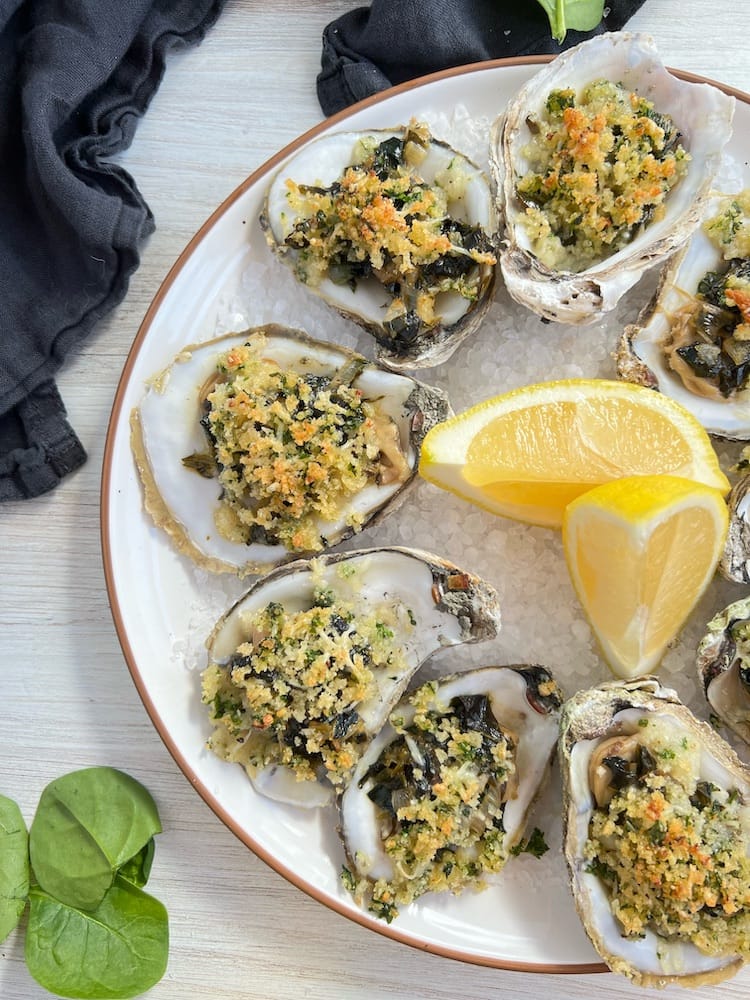 We love Seafood Appetizers like Oysters Rockefeller on a plate with lemon wedges and rock salt