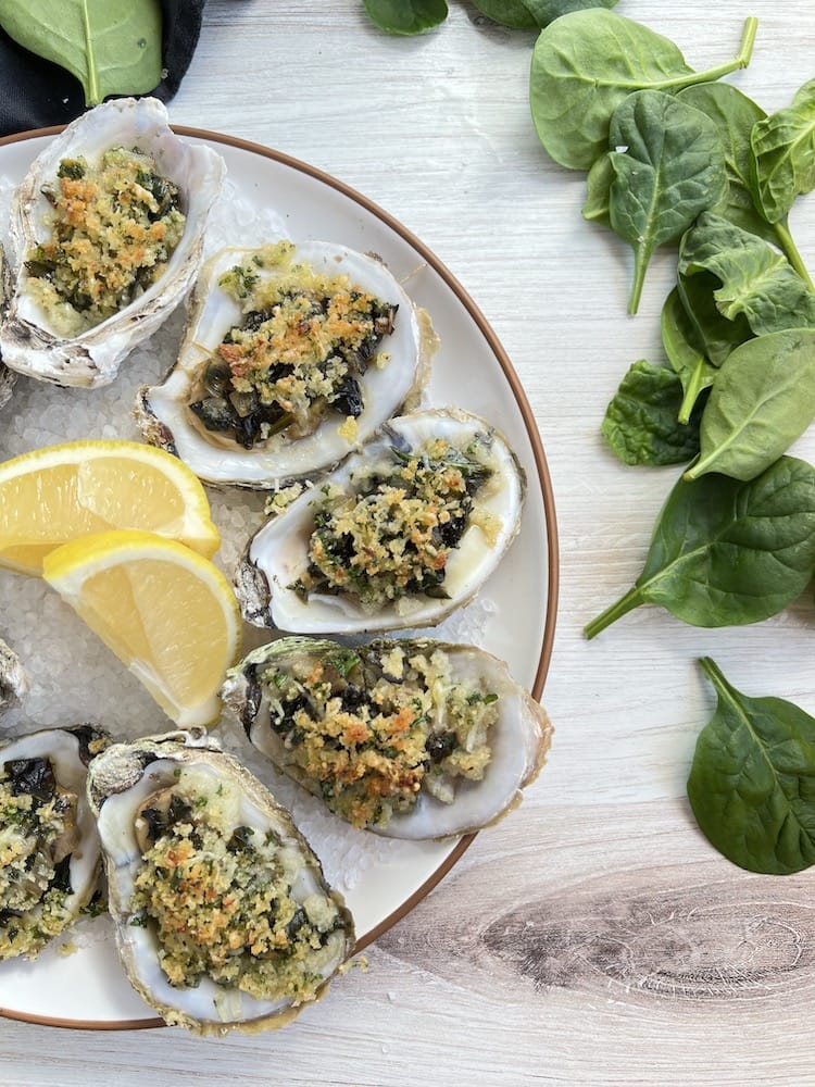 Oysters Rockefeller on a plate with lemon wedges and rock salt