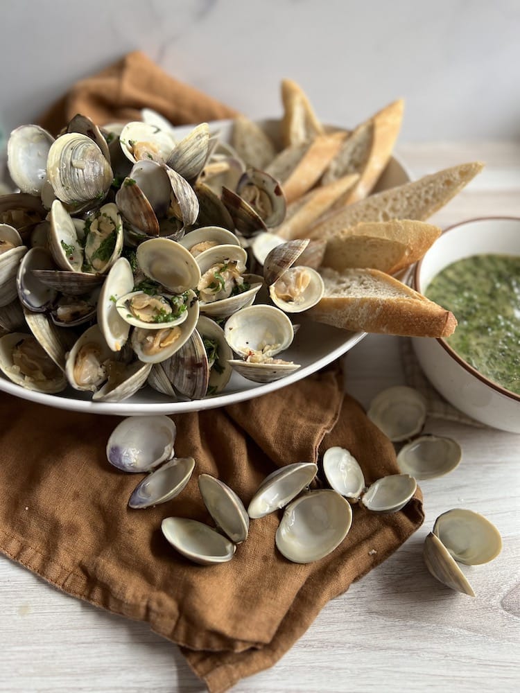 Steamed Little Neck Clams in a serving dish with sliced bread