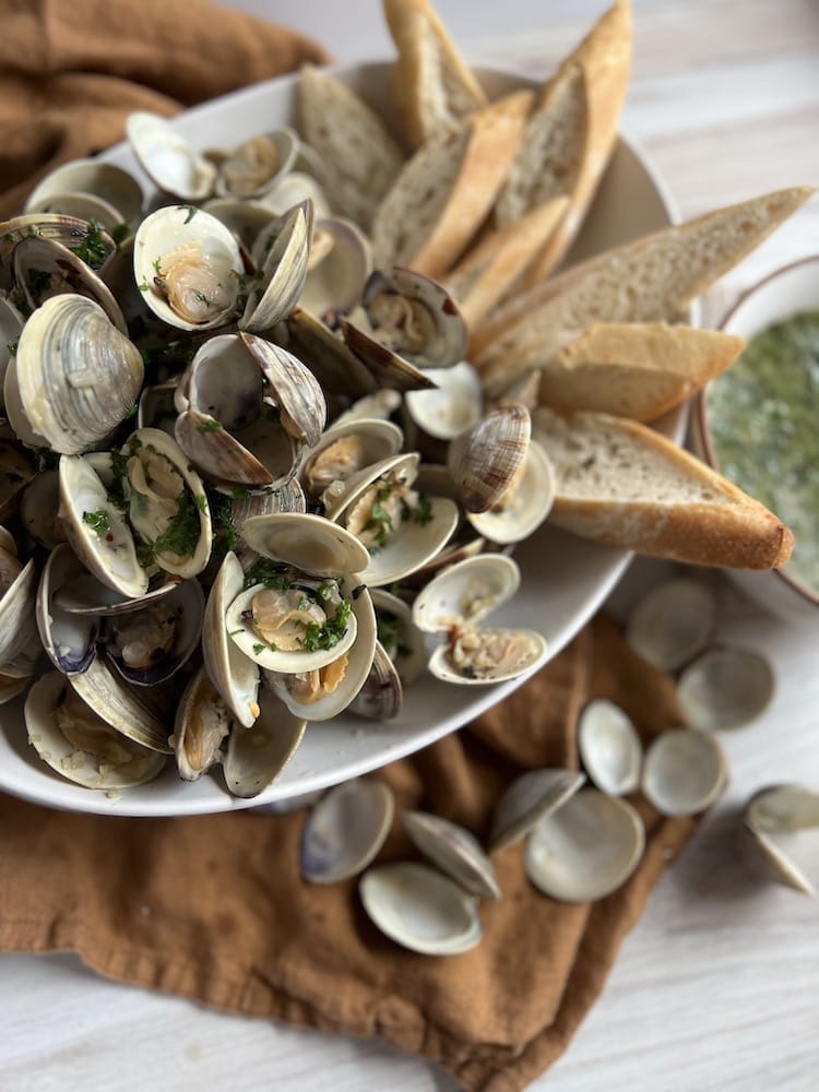 Steamed Little Neck Clams in a serving dish with sliced bread