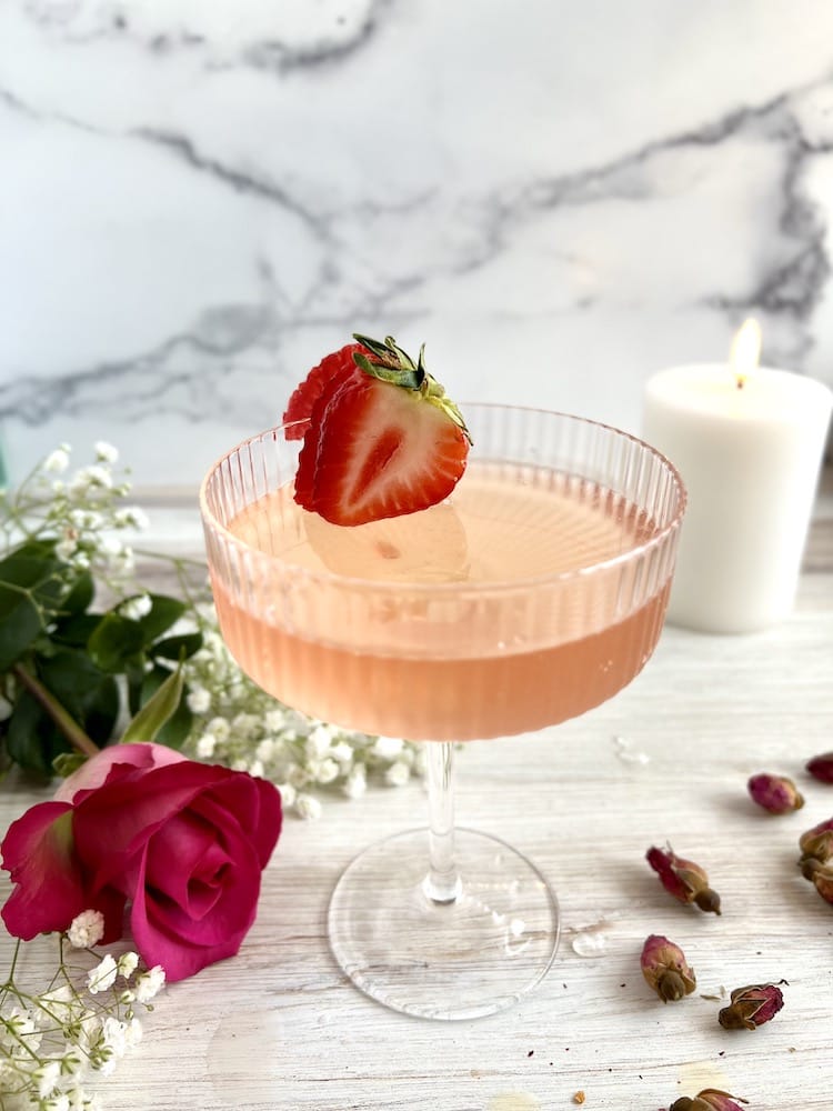 V-Day Starter Pack cocktail in a glass next to a rose, baby's breath, and a white candle