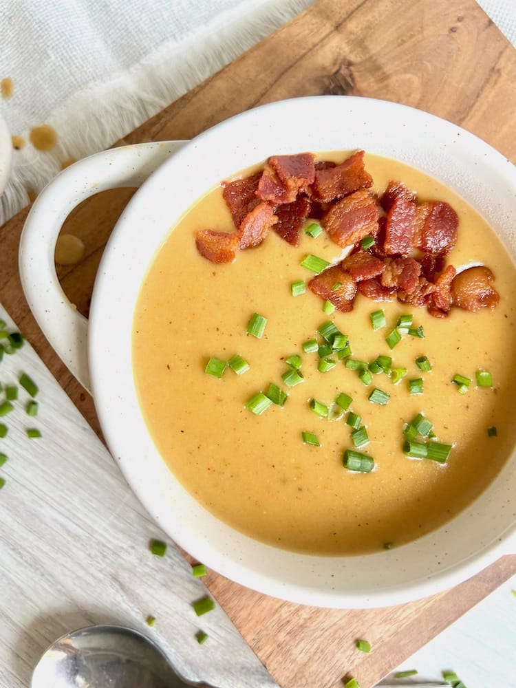 Irish Beer Cheese Soup in a bowl garnished with bacon bits and chives