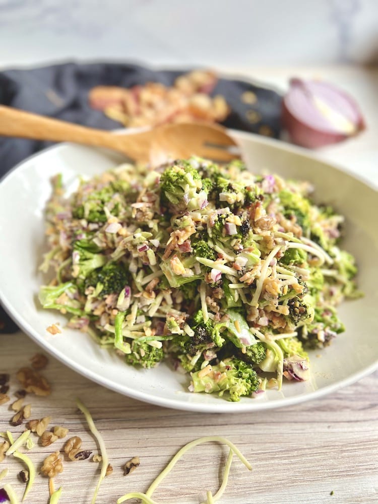 Charred Broccoli Salad in a white serving dish with wooden serving spoon