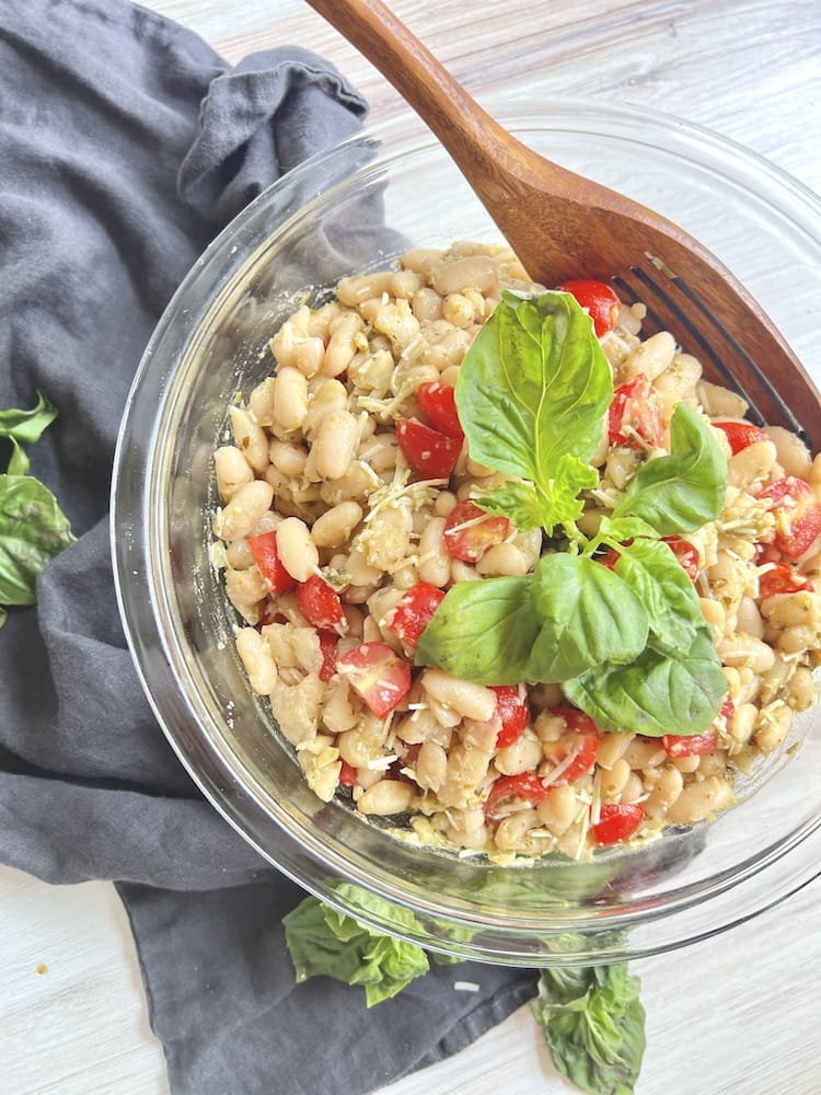 Pesto Cannellini Bean Salad in a large serving bowl with wooden spoon