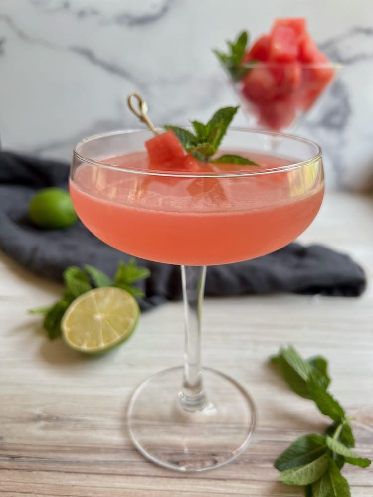 Watermelon Martini in a coupe glass with mint leaf and watermelon spear as garnish