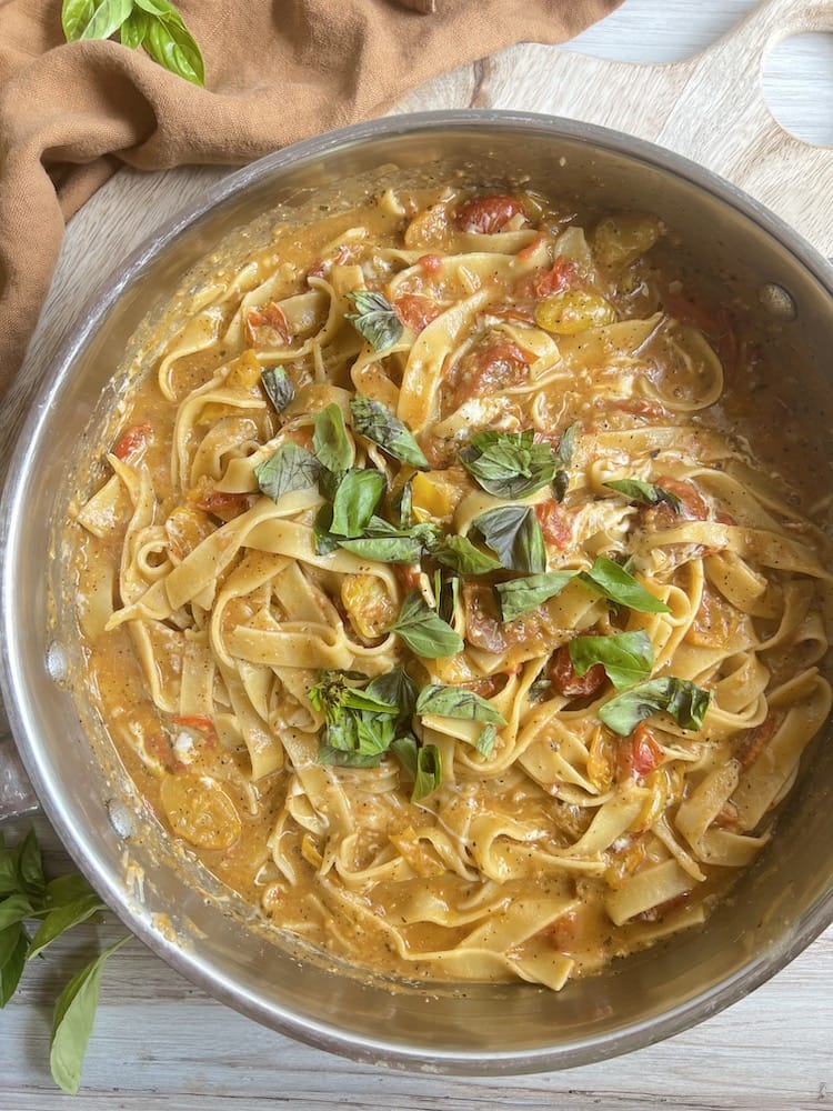 Tomato Pesto Pasta in a large metal pan with fresh basil as a garnish