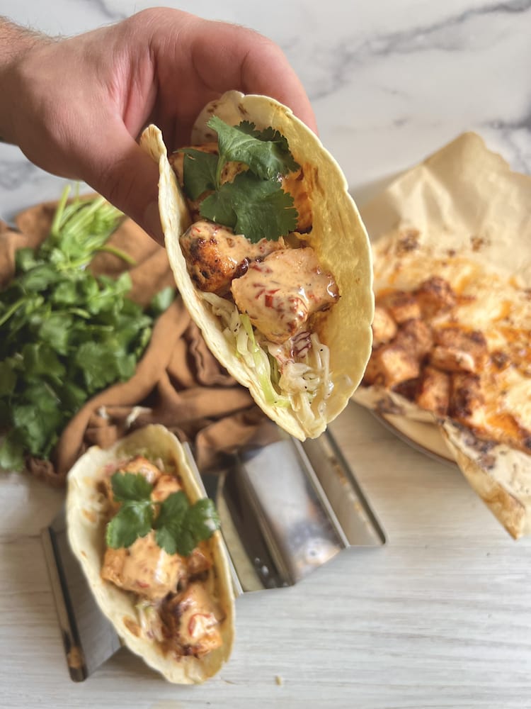 Air Fryer Chipotle Salmon Tacos with one being held toward the viewer by a hand