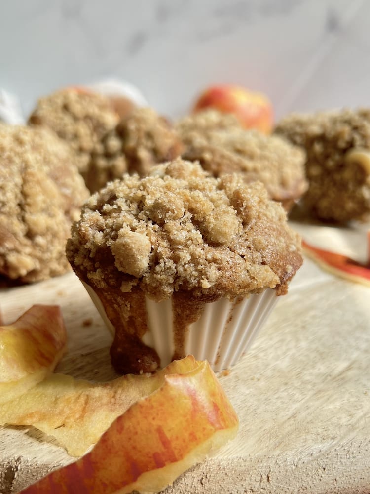 Apple Streusel Cheesecake Muffins on a cutting board with apple peels