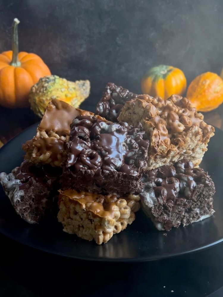 Halloween Marshmallow Treats on a black plate with small pumpkins in the background