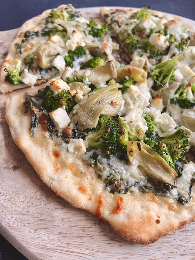 Creamed Collards and Broccoli Pizza on a wooden cutting board