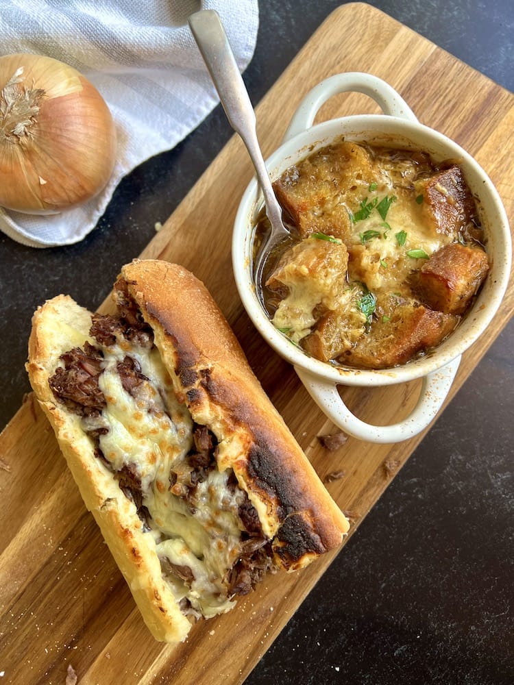 Instant Pot French Dip with a bowl of French Onion Soup on a cutting board