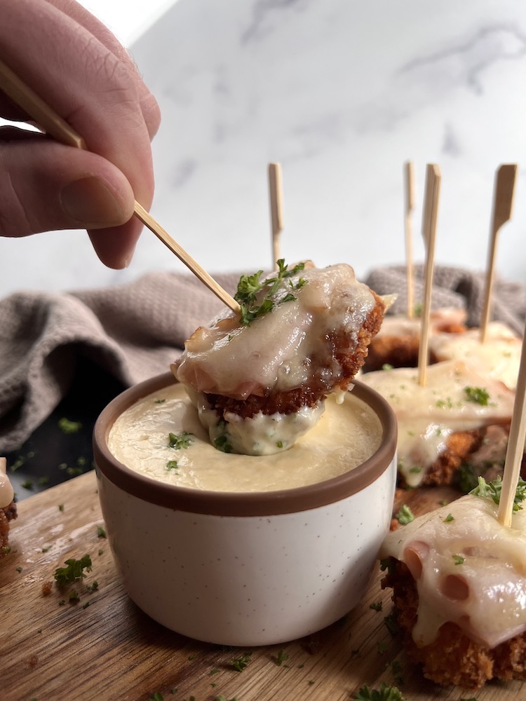Chicken Cordon Bleu Bites with one Bite being dipped into Dijon Dipping Sauce