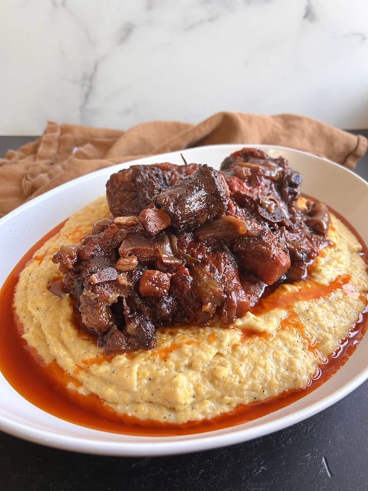 Italian Braised Oxtail served over Creamy Polenta in a large serving dish