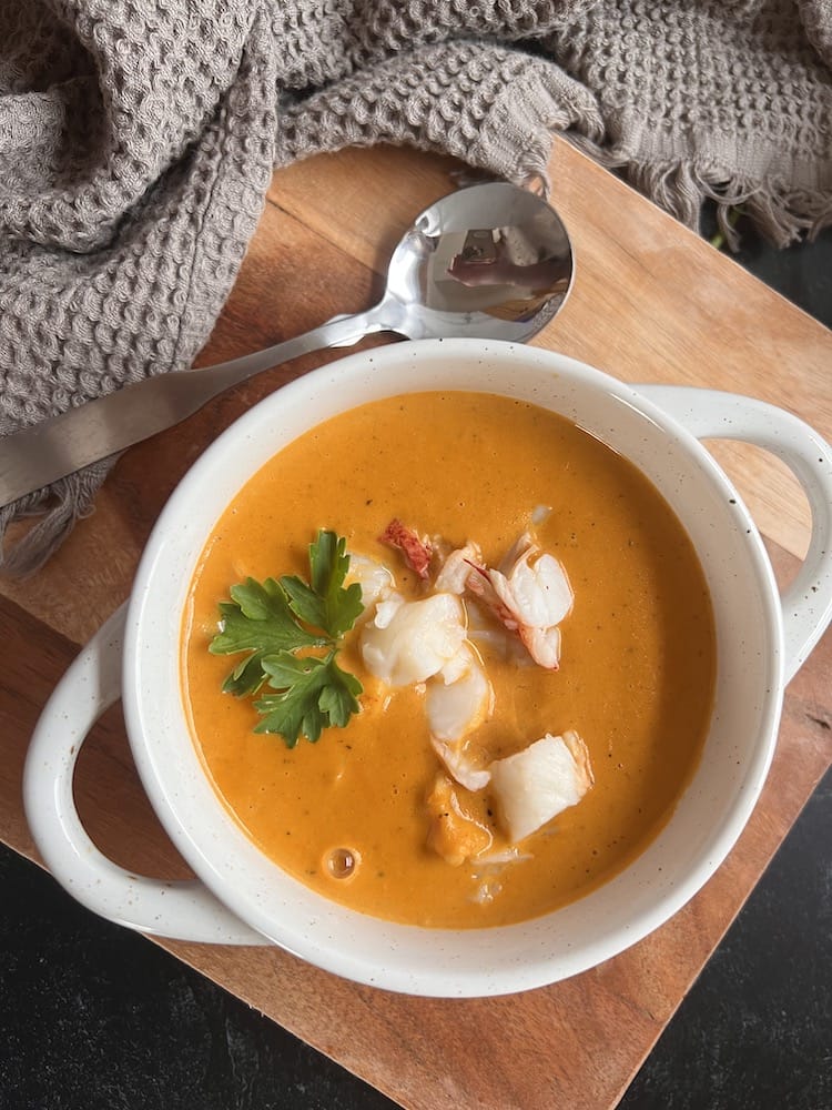 Lobster Bisque in a white bowl on a cutting board