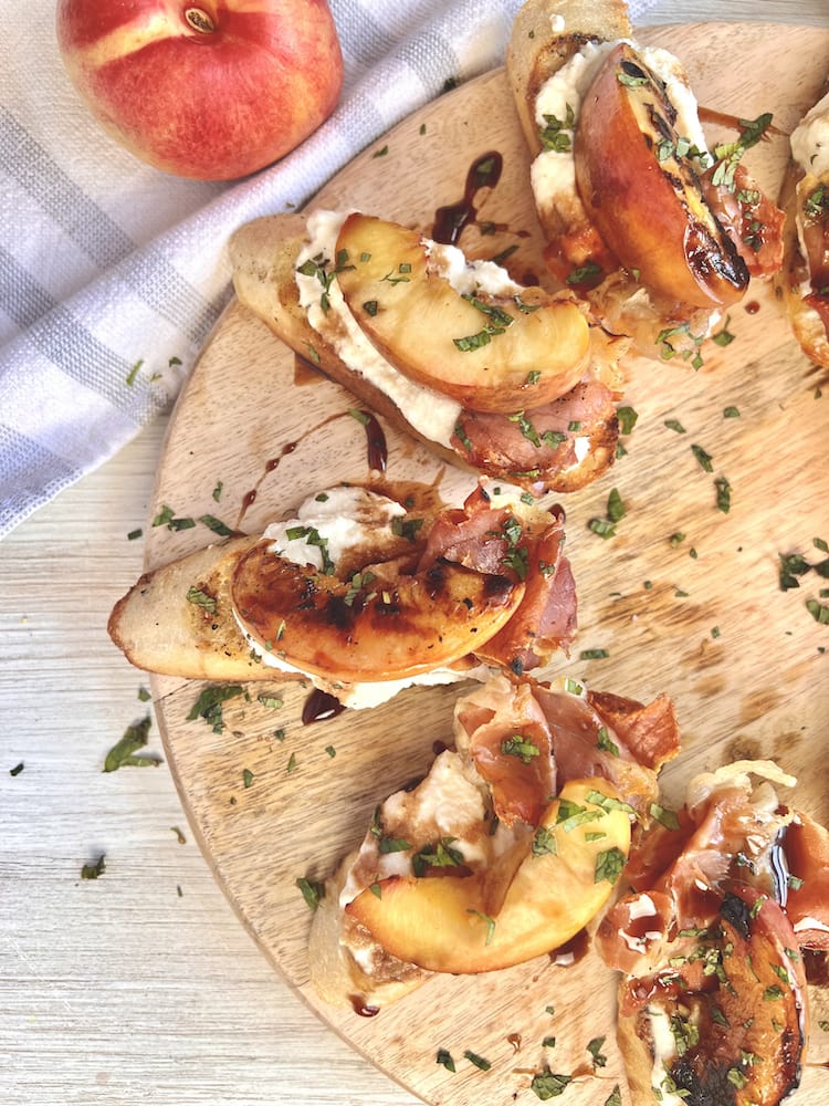 Grilled Nectarine and Prosciutto Crostini on a wooden cutting board