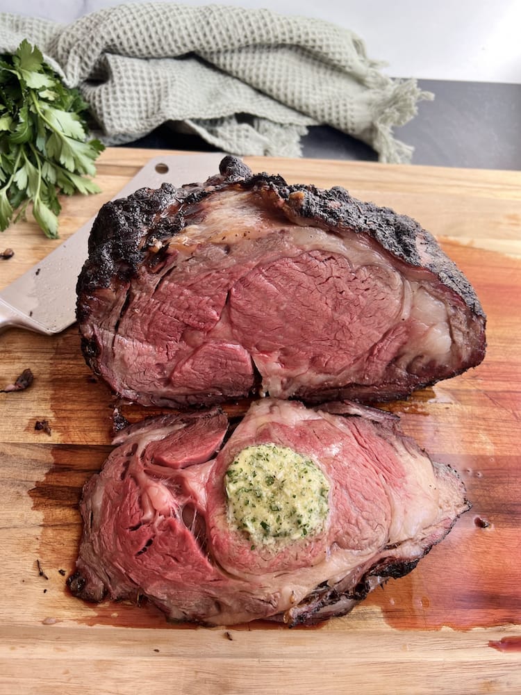 Smoked Prime Rib with garlic and horseradish compound butter on a wooden cutting board