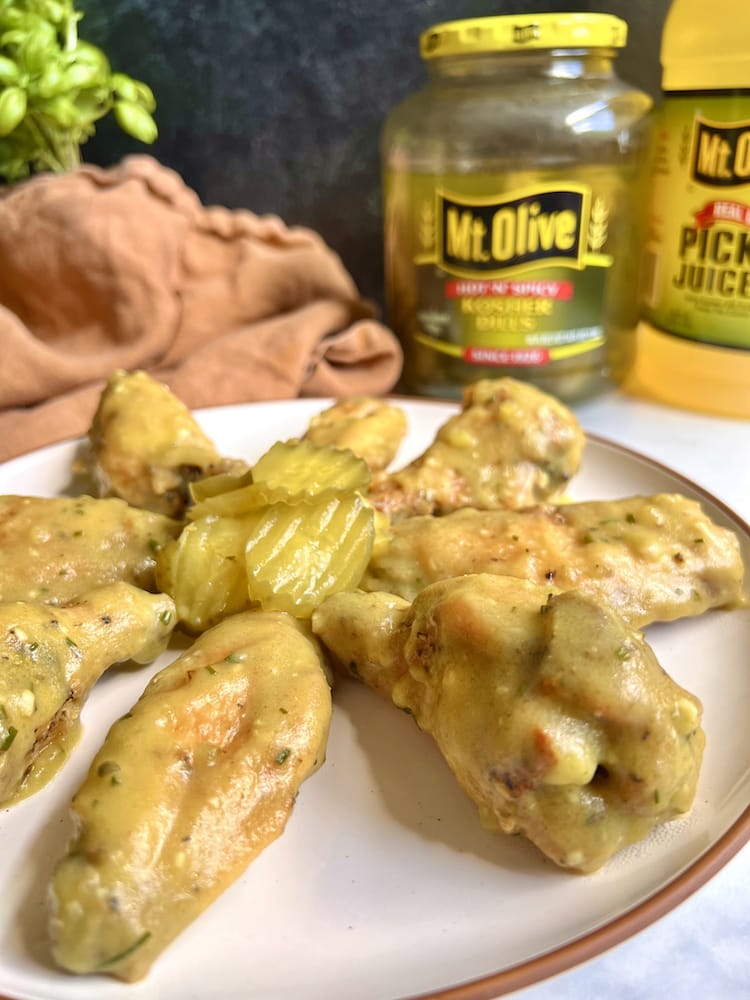 Garlic Dill Pickle Wings on a white plate with pickle chips in the center