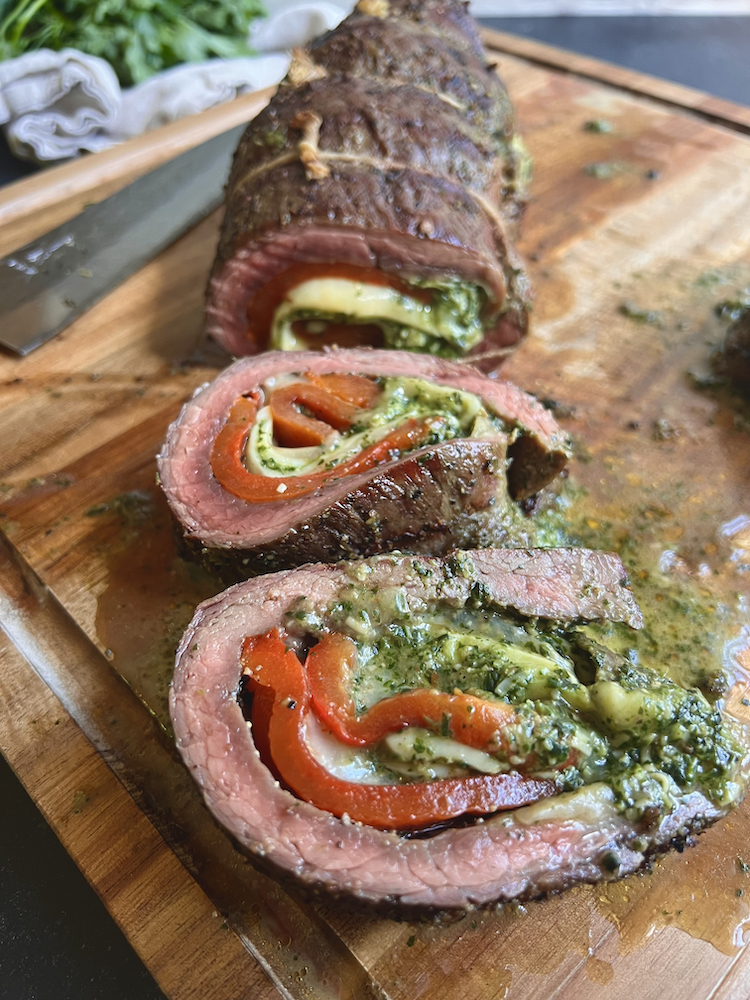 Grilled Italian Beef Roulade sliced and laid on a wooden cutting board