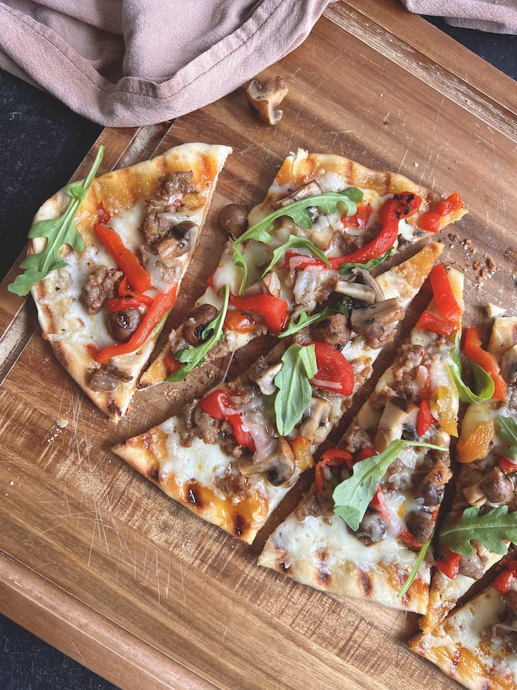 Italian Sausage and Mushroom Flatbread cut into slices on a wooden cutting board