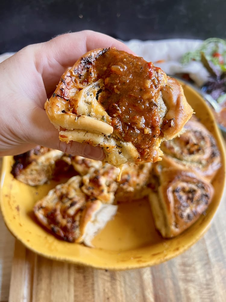 Chicken Parm Pull Apart Bread held in a hand toward the viewer and the piece of bread has marinara sauce on it