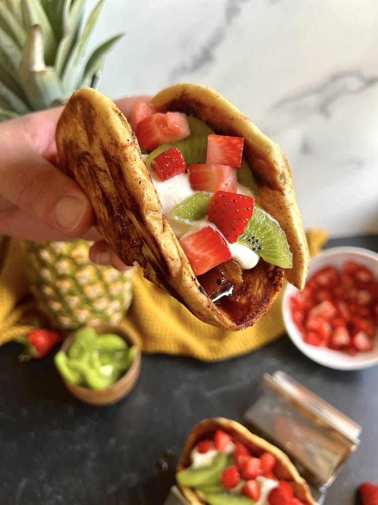 Cinnamon Bun Dessert Tacos with one held in hand toward the camera