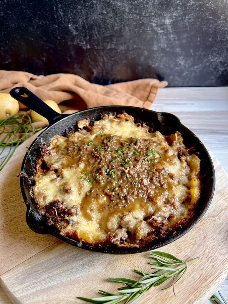 Beef and Potato Skillet Pie in a cast iron pan on a wooden cutting board