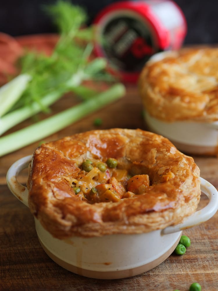 Two Lobster Pot Pies on a wooden cutting board with fresh fennel in the background