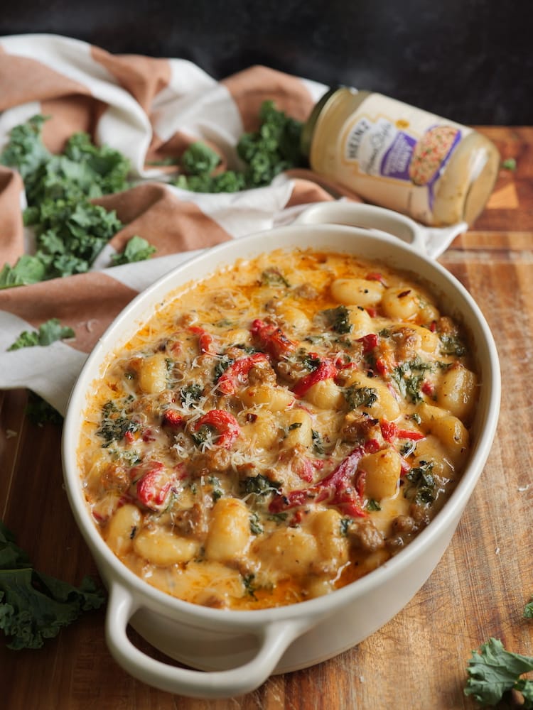 Tuscan Gnocchi al Forno on a wooden cutting board with fresh kale and empty gravy jar behind it