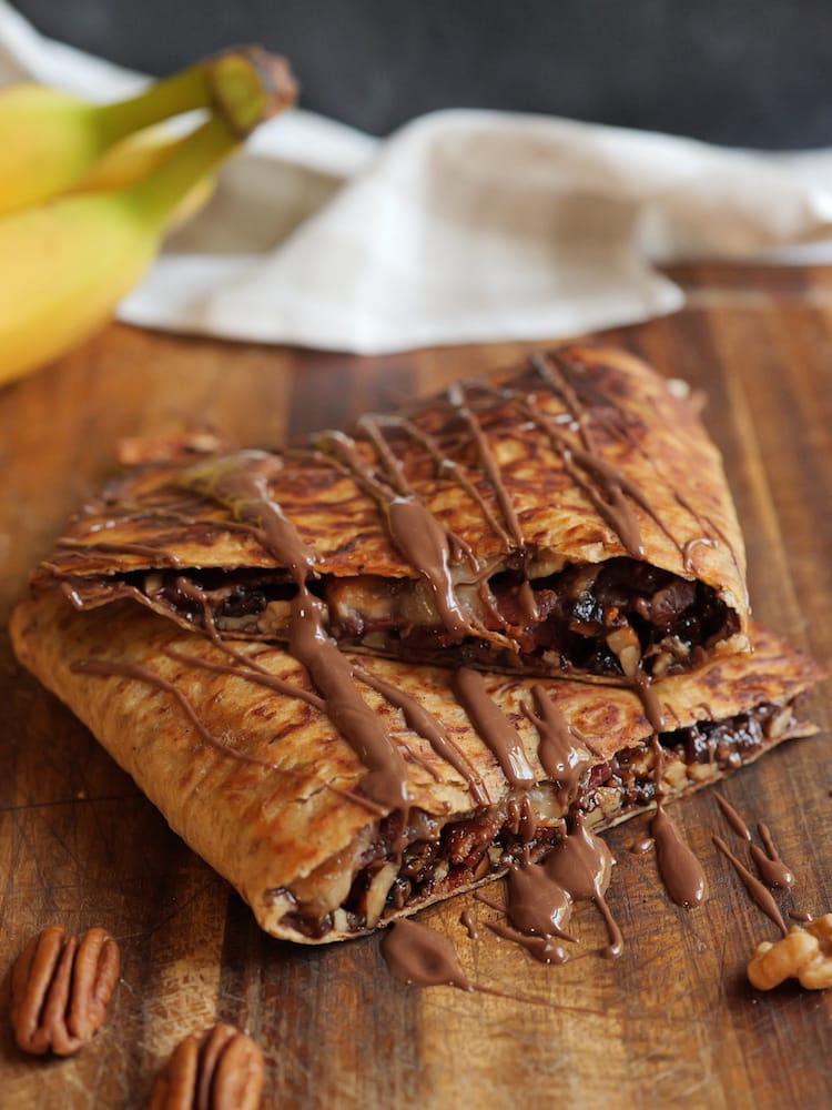 The King's Banana Nut Crunch on a wooden cutting board with a banana bunch in the background