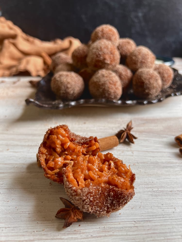 Thai Tea Dessert Arancini with one arancino sliced open and laying in front of a pile of arancini