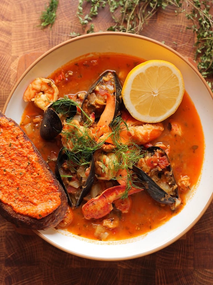 Lobster Bouillabaisse in a white pasta bowl with fresh thyme above it