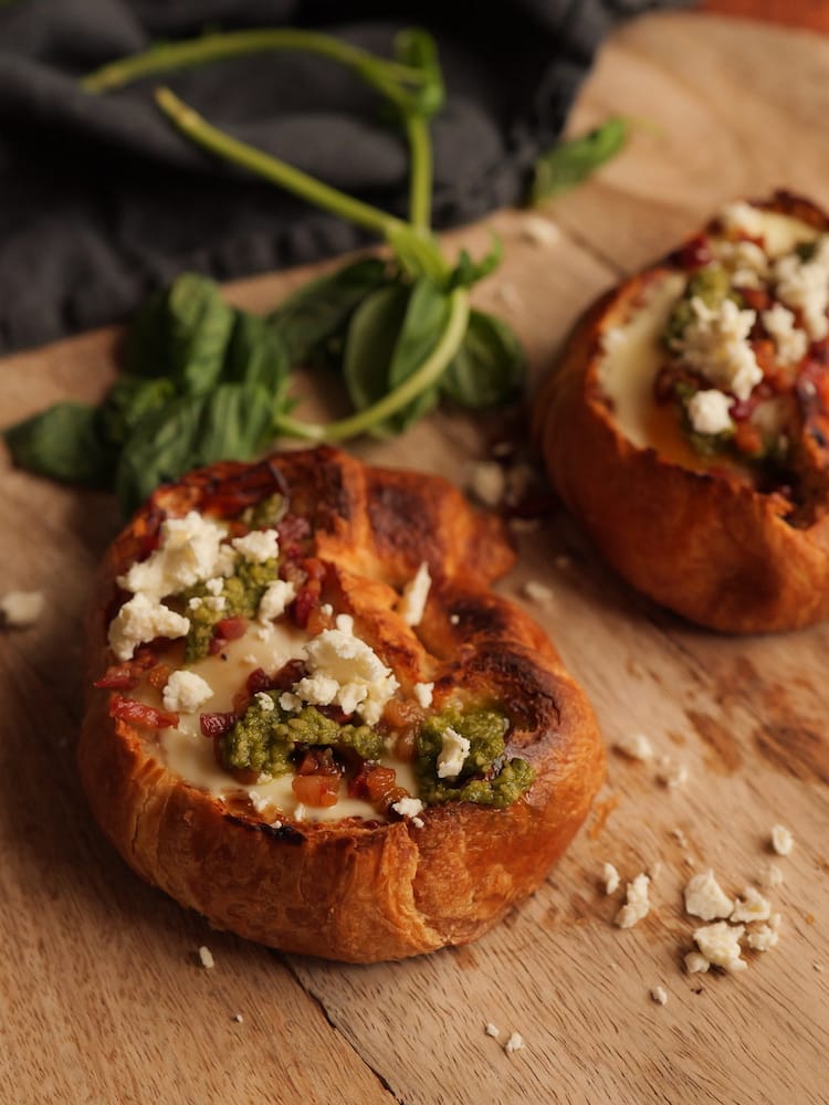 2 Tomato and Egg Stuffed Croissants ona cutting board with fresh basil