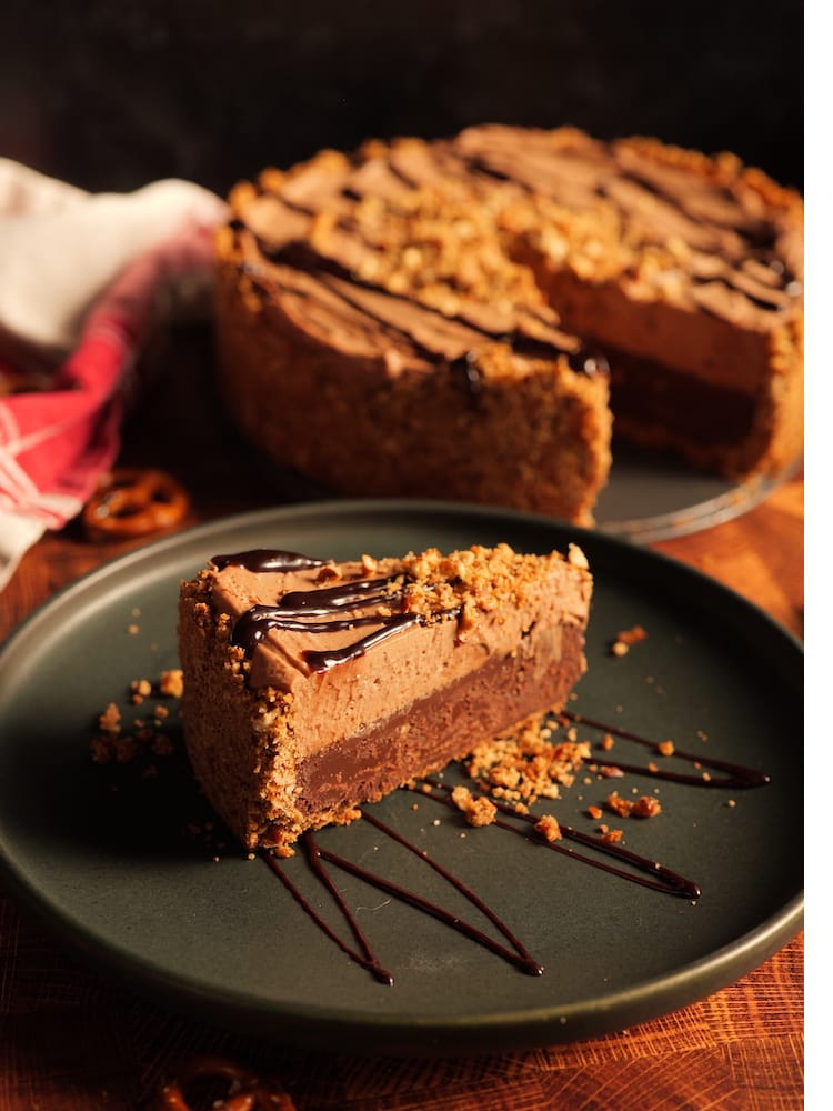 A Mexican Hot Chocolate Pie slice on a black plate with the rest of the pie in the back ground.