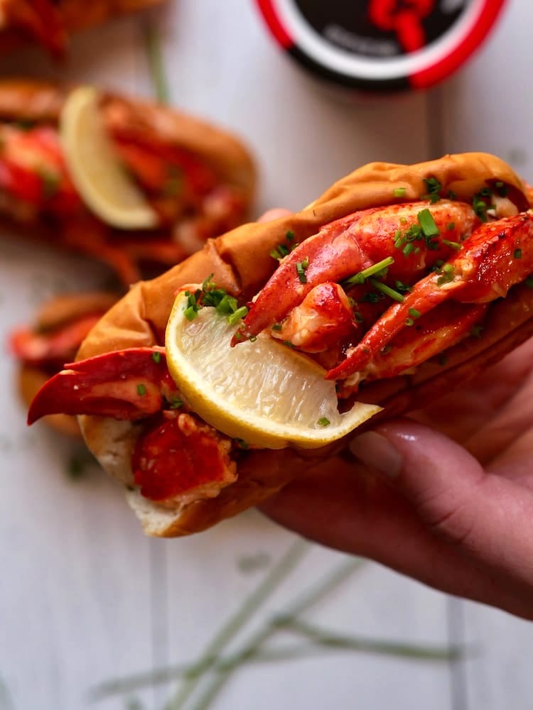 Three Connecticut Lobster Roll next to a bowl of corn on the cob