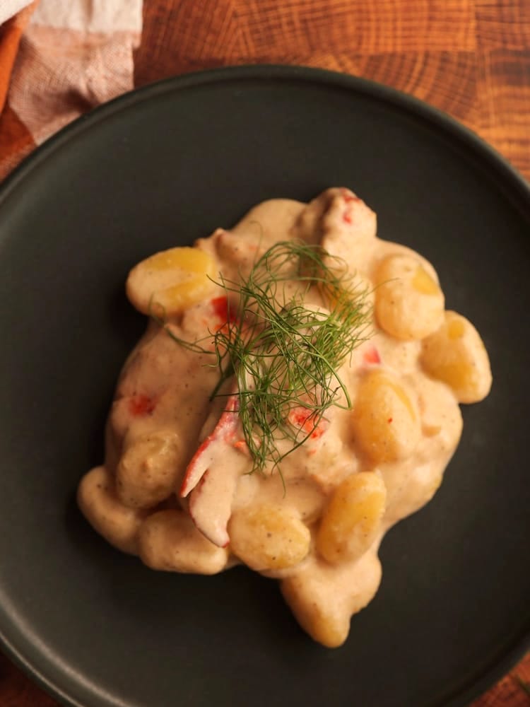 Lobster and Gnocchi with Fennel Cream Sauce on a black plate