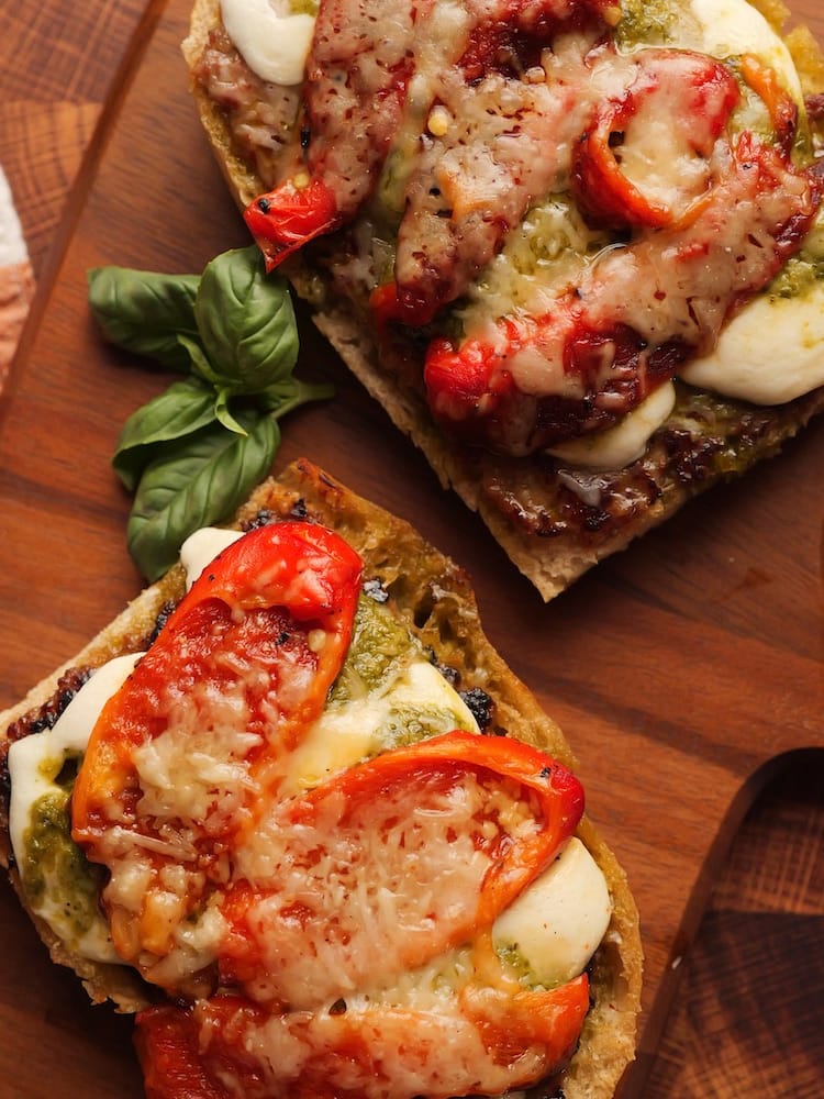 Toasted Tuscan Sausage Sandwich on a wooden cutting board with fresh basil leaves beside it