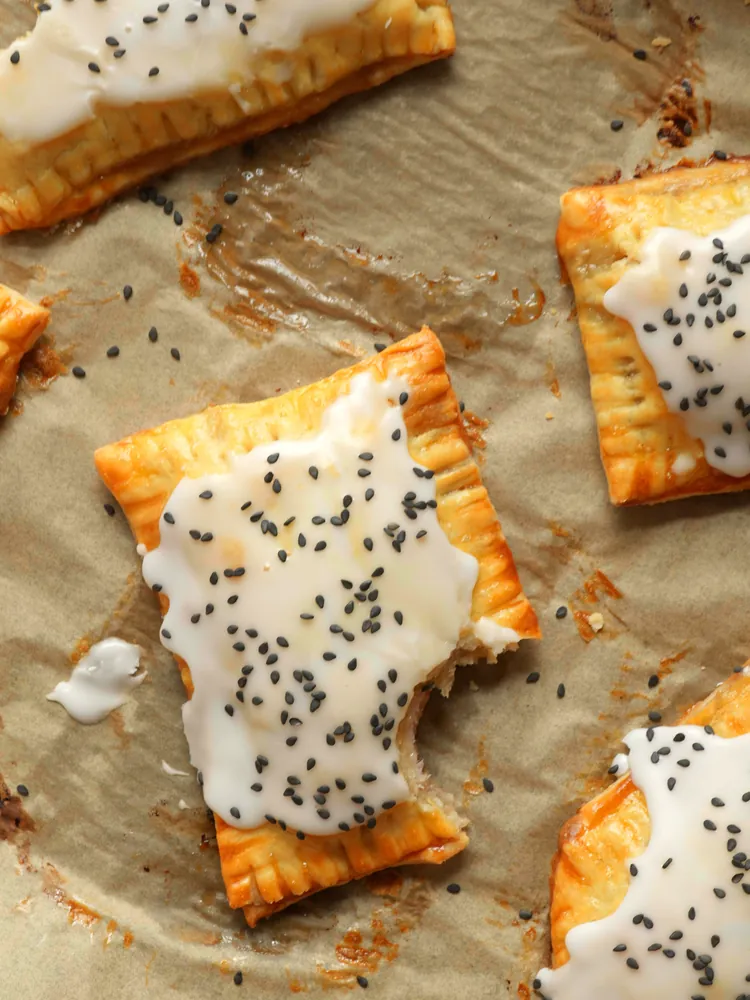 Monte Cristo Pop Tarts on a parchment-lined baking sheet, the center one with a bite taken out of the corner