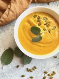 Creamy Butternut Squash Bisque in a bowl garnished with sage leaves and pepitas