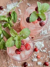 Holiday Sangria in two glasses garnished with mint and fresh cranberries