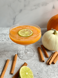 Pumpkin Spice Margarita in a glass surrounded by cinnamon sticks and pumpkins